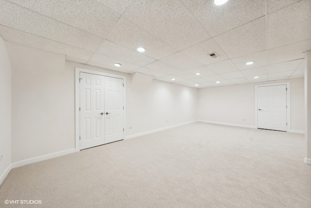 basement with a paneled ceiling and carpet