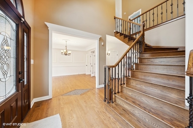 foyer entrance with a notable chandelier, light wood-type flooring, and crown molding