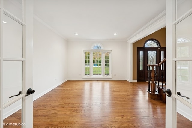 foyer entrance with hardwood / wood-style floors, crown molding, and french doors