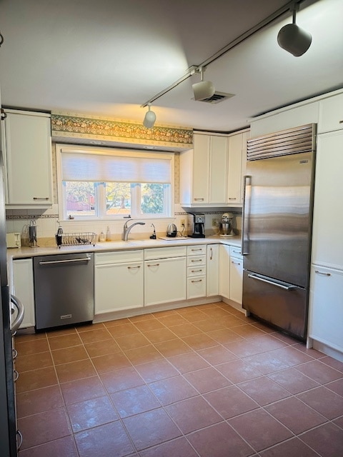 kitchen featuring tasteful backsplash, appliances with stainless steel finishes, sink, and white cabinets