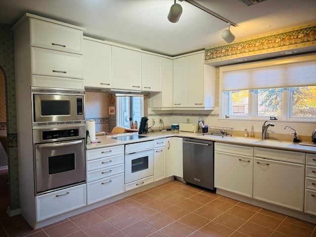 kitchen with appliances with stainless steel finishes, white cabinets, and tasteful backsplash