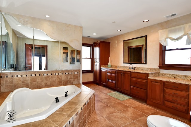 bathroom with tile patterned flooring, vanity, a wealth of natural light, and tiled tub