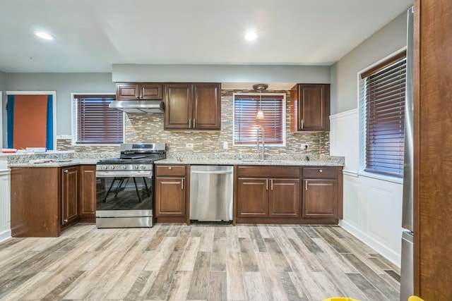 kitchen with light hardwood / wood-style floors, appliances with stainless steel finishes, and decorative backsplash