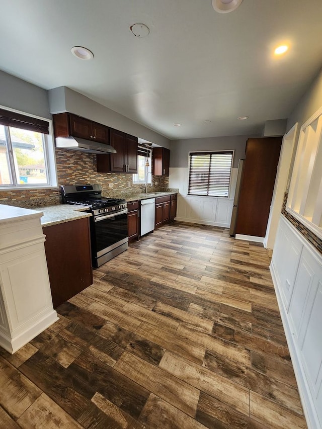 kitchen featuring backsplash, white dishwasher, stainless steel range with gas stovetop, dark brown cabinetry, and dark wood-type flooring