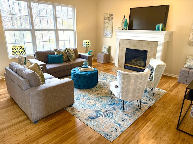 living room with a tiled fireplace and light hardwood / wood-style flooring