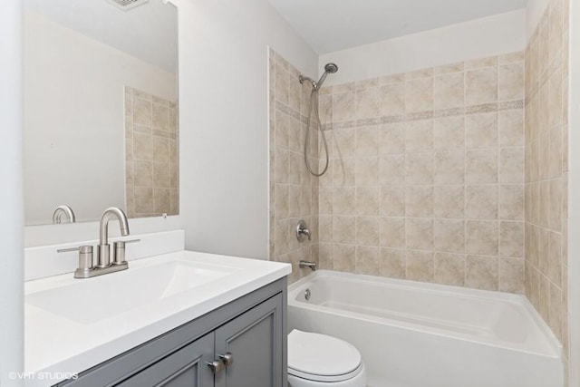 full bathroom featuring vanity, tiled shower / bath, and toilet