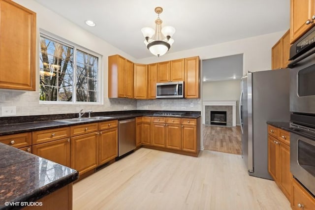 kitchen with appliances with stainless steel finishes, light hardwood / wood-style floors, sink, and decorative backsplash