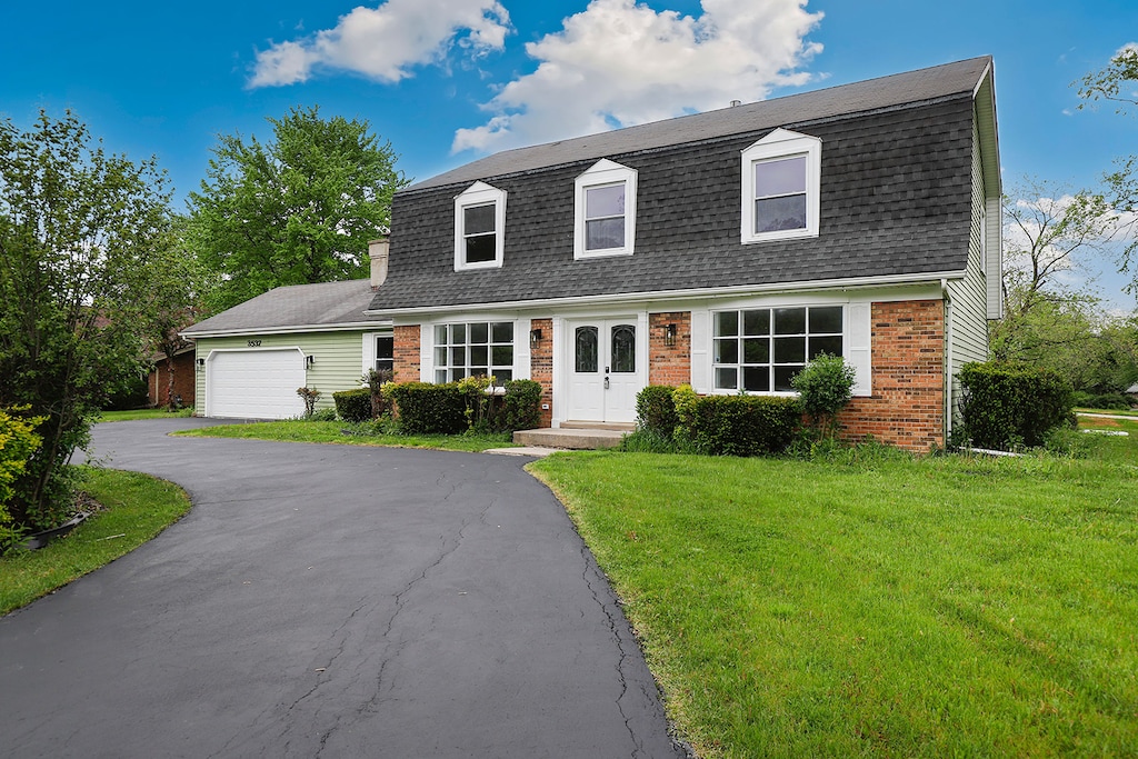 new england style home featuring a front yard and a garage