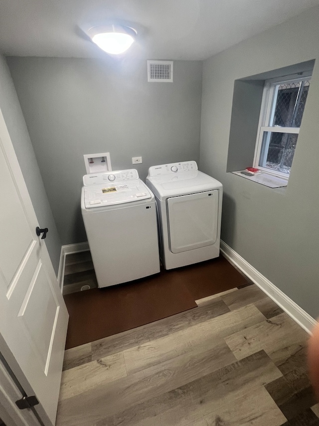 clothes washing area featuring wood-type flooring and washing machine and clothes dryer