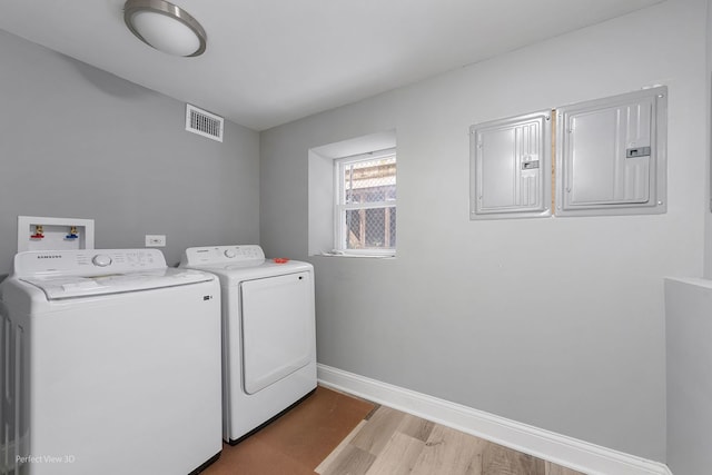 laundry area with electric panel, light hardwood / wood-style flooring, and washer and clothes dryer