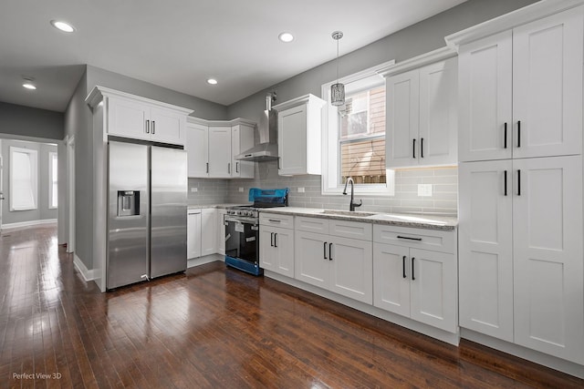 kitchen featuring appliances with stainless steel finishes, white cabinetry, dark hardwood / wood-style floors, wall chimney exhaust hood, and sink