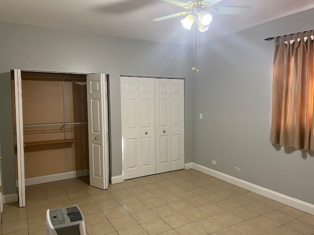 unfurnished bedroom with light tile patterned floors, ceiling fan, and multiple closets