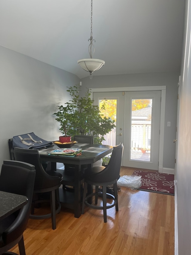 dining area with hardwood / wood-style flooring, lofted ceiling, and french doors