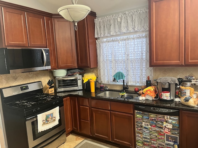 kitchen featuring dark stone counters, sink, appliances with stainless steel finishes, tasteful backsplash, and decorative light fixtures