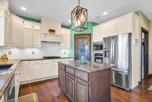 kitchen with a center island, stainless steel appliances, pendant lighting, light stone counters, and dark hardwood / wood-style floors