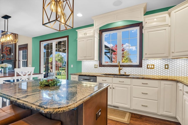 kitchen with a kitchen breakfast bar, dark hardwood / wood-style floors, dishwasher, pendant lighting, and sink