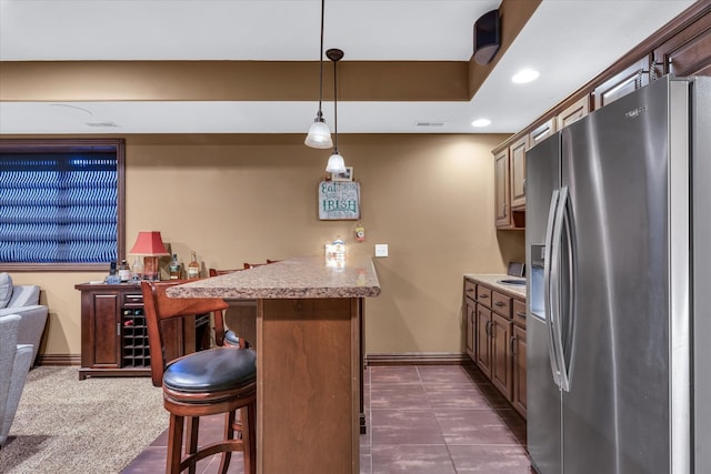 bar with stainless steel fridge, dark tile patterned floors, and decorative light fixtures