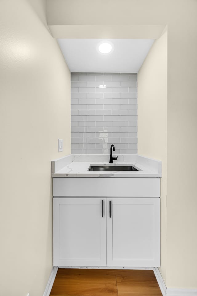 bathroom with vanity, hardwood / wood-style flooring, and backsplash