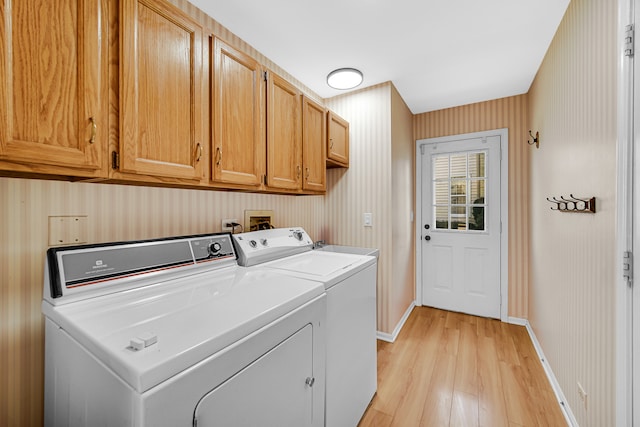 washroom featuring cabinets, light hardwood / wood-style flooring, and washer and dryer