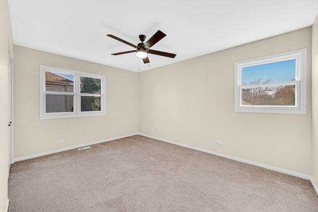 unfurnished room featuring ceiling fan, light carpet, and plenty of natural light