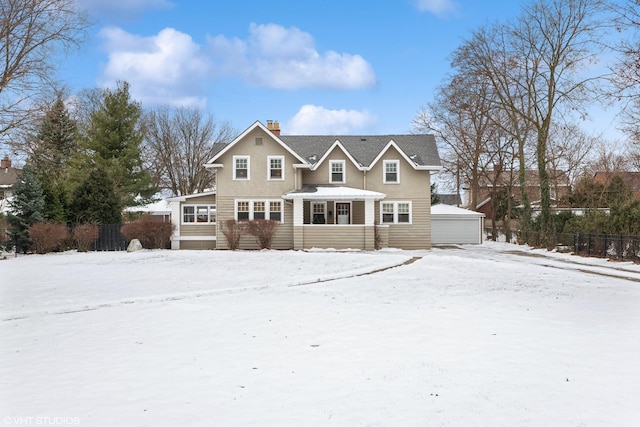 snow covered back of property featuring a garage