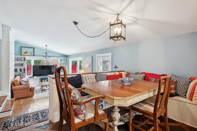 dining space featuring breakfast area, a notable chandelier, vaulted ceiling, and hardwood / wood-style floors