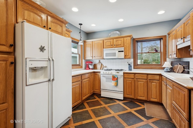 kitchen featuring backsplash, white appliances, decorative light fixtures, and sink