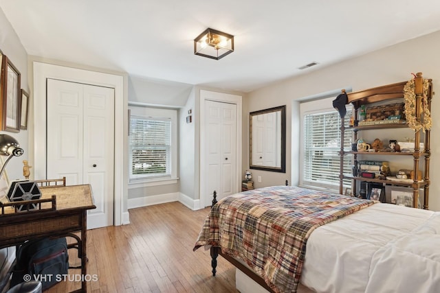 bedroom featuring two closets and light hardwood / wood-style floors