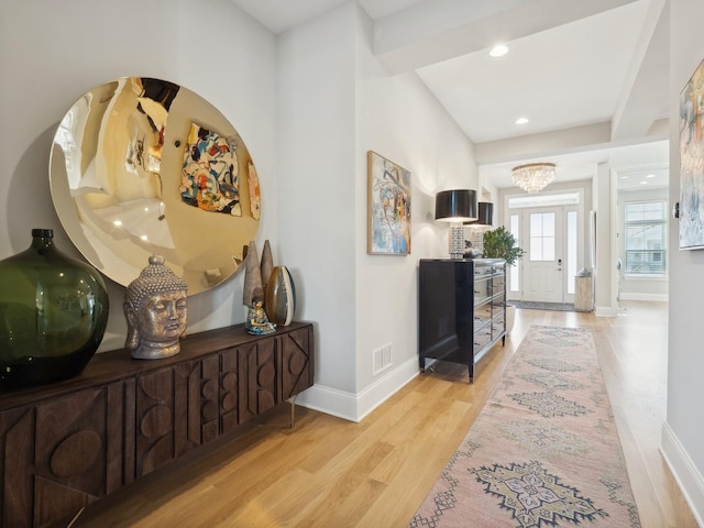 hallway with an inviting chandelier and light wood-type flooring