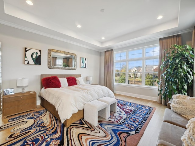 bedroom featuring a raised ceiling and light hardwood / wood-style flooring