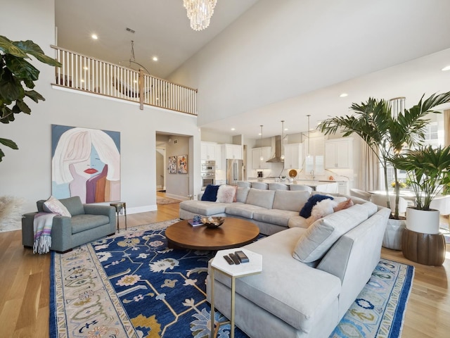 living room with a towering ceiling, light hardwood / wood-style floors, and an inviting chandelier