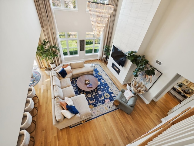 living room with a chandelier, wood-type flooring, and a towering ceiling