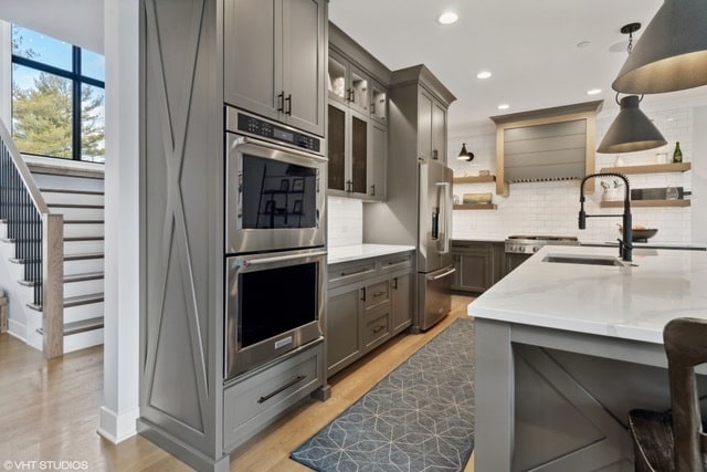 kitchen with pendant lighting, light stone counters, stainless steel appliances, and tasteful backsplash