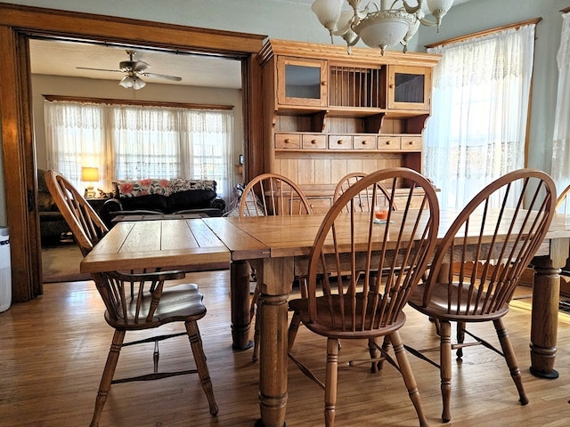 dining space with light wood-type flooring and ceiling fan with notable chandelier