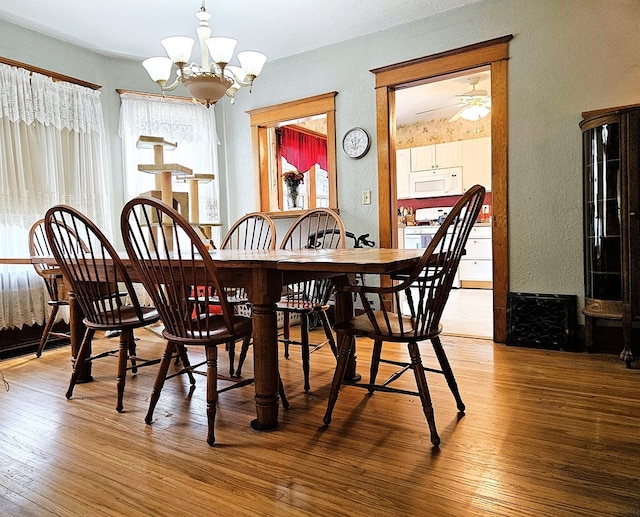 dining room featuring hardwood / wood-style floors and ceiling fan with notable chandelier