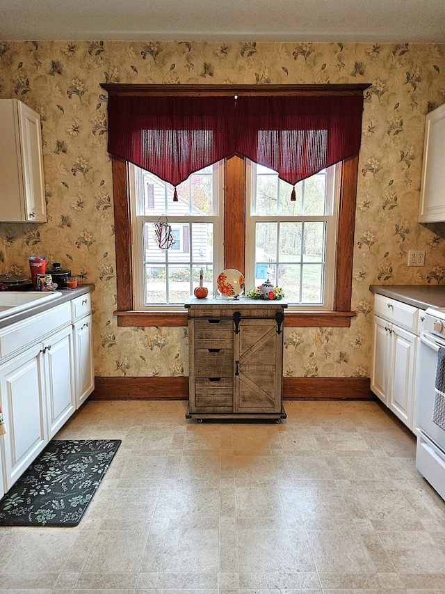 kitchen with white range, sink, and white cabinetry