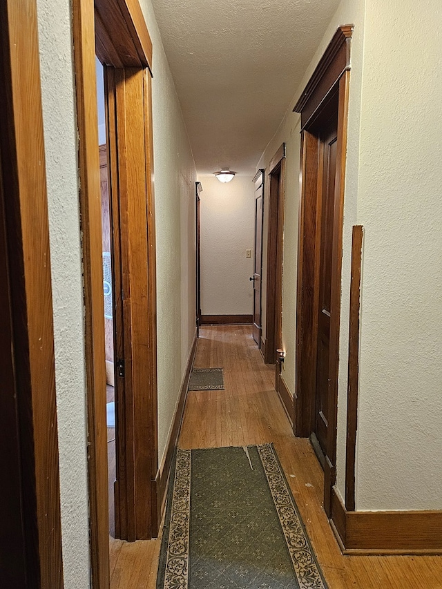 corridor featuring wood-type flooring and a textured ceiling