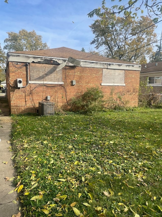 view of side of home featuring cooling unit and a lawn