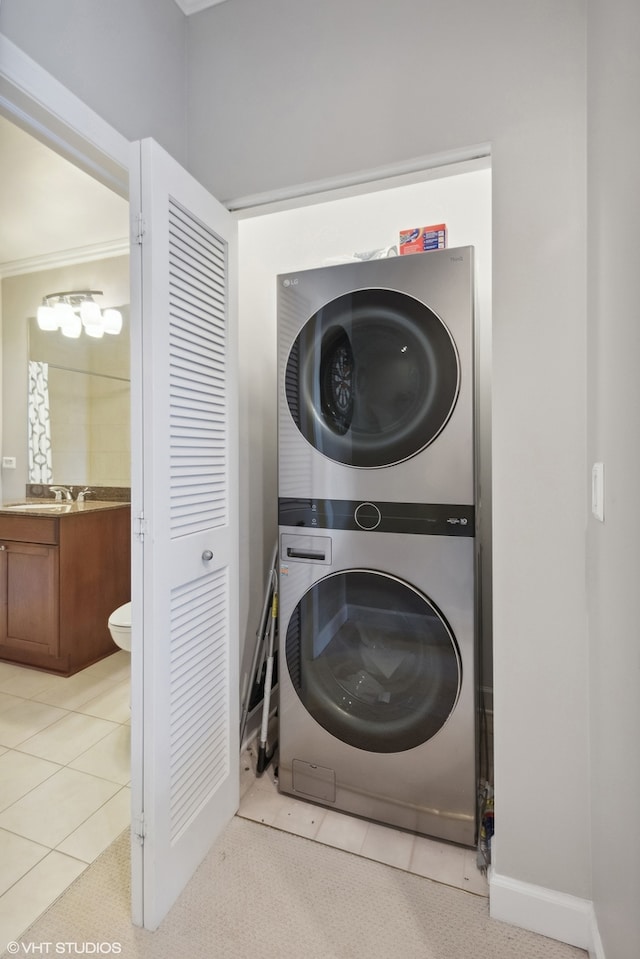 laundry area featuring ornamental molding, stacked washer and dryer, and light tile patterned floors