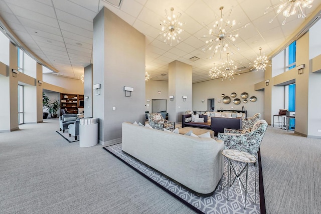 carpeted living room featuring a towering ceiling and a chandelier