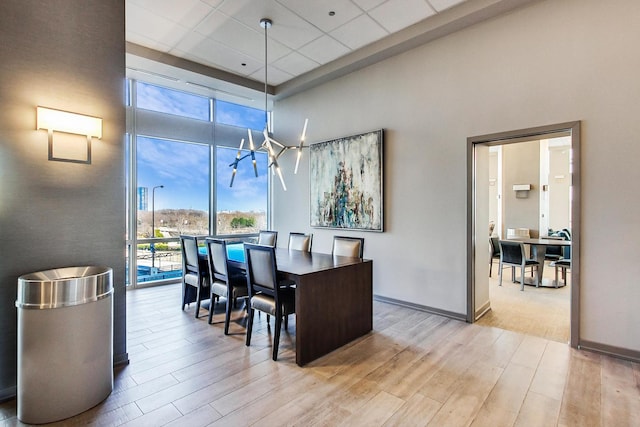 dining space featuring light wood-type flooring, a towering ceiling, and plenty of natural light