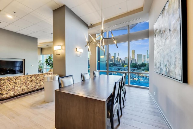 dining space featuring a drop ceiling and light hardwood / wood-style flooring