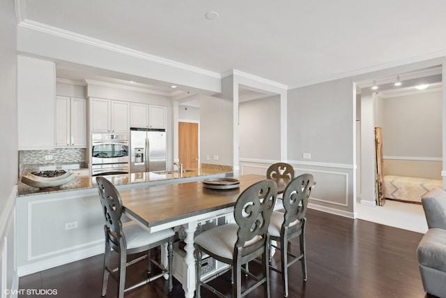 dining room with ornamental molding, sink, and dark hardwood / wood-style floors