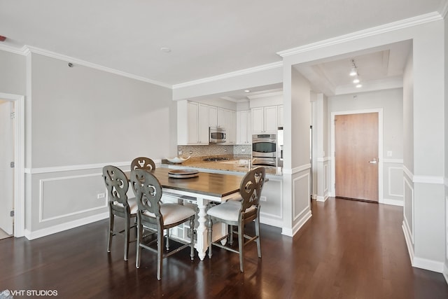 dining room with ornamental molding, dark wood-type flooring, and track lighting