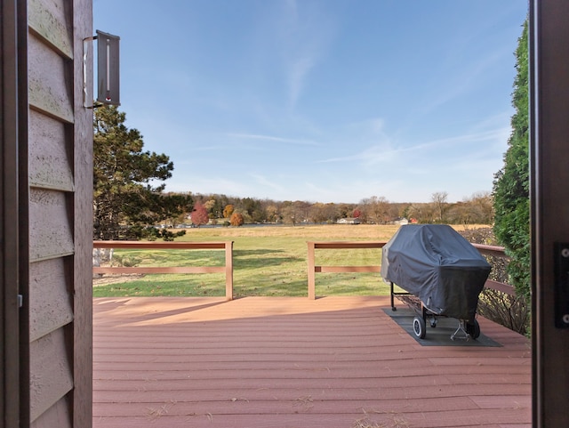 wooden terrace with a lawn, a grill, and a rural view