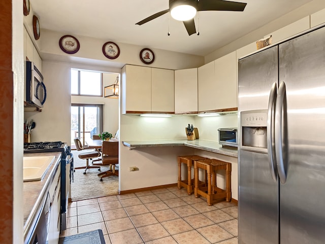 kitchen featuring ceiling fan, white cabinets, stainless steel appliances, and light tile patterned floors