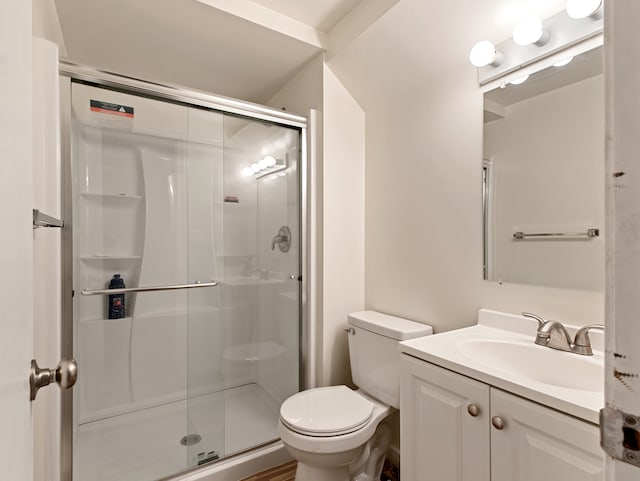 bathroom featuring vanity, a shower with shower door, and toilet