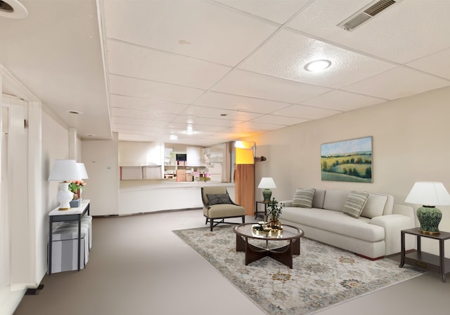 living room featuring concrete floors and a drop ceiling