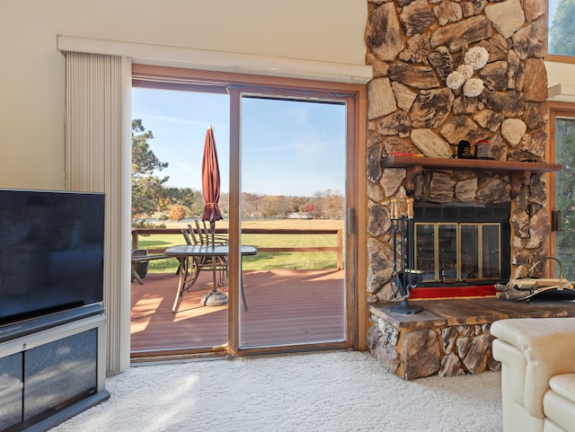 doorway to outside with carpet flooring, a healthy amount of sunlight, and a stone fireplace