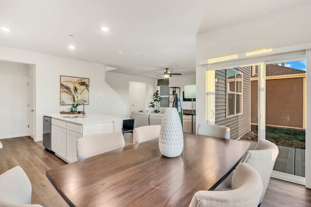 dining space with light hardwood / wood-style floors, ceiling fan, and sink